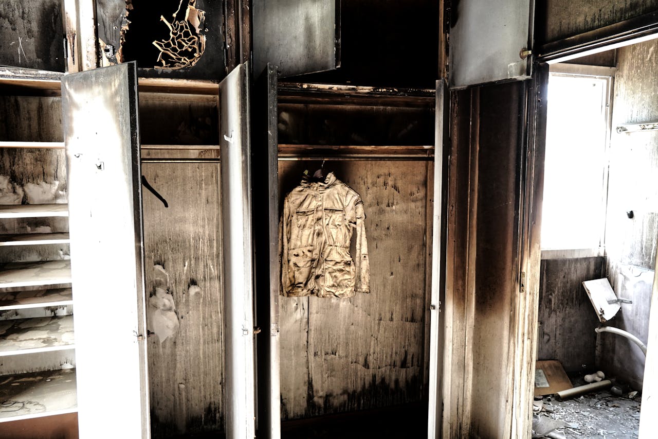 why-choose-us A haunting view of an abandoned, burned-out room with a decaying jacket hanging in a closet.