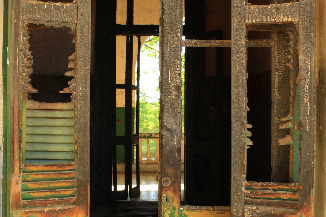 gallery-1 Charred and damaged doorway leading into an abandoned structure, highlighting decay.