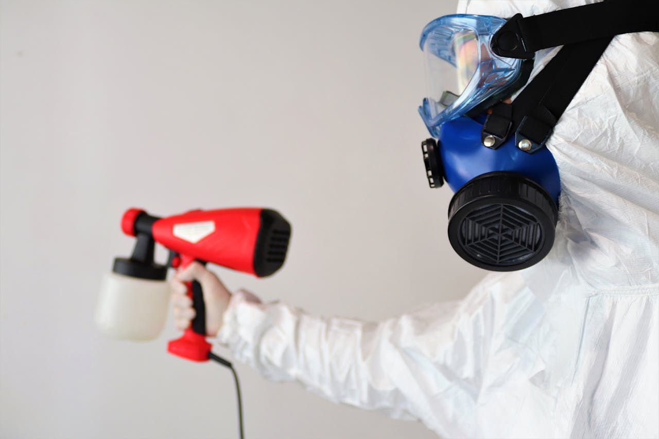 gallery-6 A worker in protective gear uses a disinfectant spray indoors.